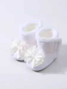 Detail der weichen Plüschtextur und der zarten Spitzenschleife dieser Babystiefel
