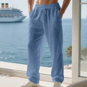 Casual blue loose linen trousers for men shown in a scenic vacation seaside balcony setting