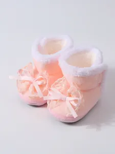 Nahaufnahme von rosa Baby-Winterstiefeln mit weichem Plüschfutter und Spitze-Schleife.