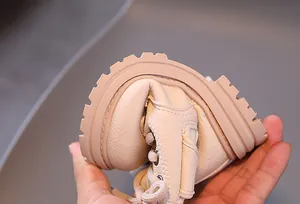 Detail close-up showing the flexible rubber sole of a beige children's Martin boot.