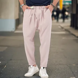 Men's pale pink casual harem pants with dropped crotch and tapered cuffed hem.