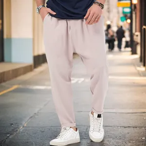 Detail view of men's stylish beige harem pants styled with sneakers on city street