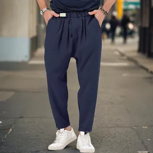 Detail view of men's navy blue drop crotch harem pants worn by model in street setting
