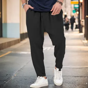 Men's stylish black drop-crotch harem pants lifestyle shot in urban street environment