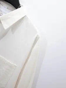 Gedetailleerd zicht op een wit herenoverhemd met lange mouwen en een borstzakje