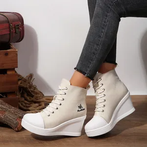 Macro view of women's lace-up wedge canvas ankle boots with butterfly logo embroidery.