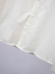 Detailweergave van een wit herenoverhemd met linnenstructuur, knopen en zoom.