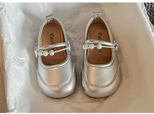 Nahaufnahme silberner Mädchen-Mary Janes mit elegantem Perlenriemen