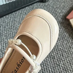 Detailaufnahme der beigen Mädchen-Mary-Janes mit elegantem Perlenriemen.