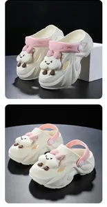 Nahaufnahme der Kinder-Clogs in Weiß mit niedlichen Wolken-Anhängern und rosa Riemen