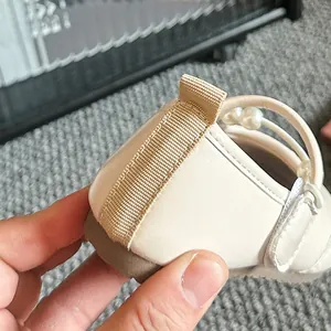 Detailansicht cremefarbener Mädchen-Ballerinas mit Perlenriemen und weicher Sohle