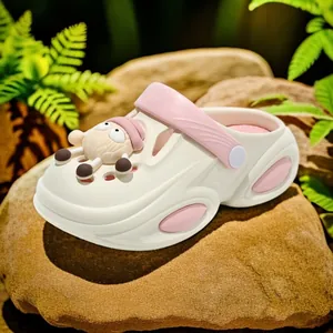 Cream kids clogs with pink strap and cute sheep charm on natural stone background