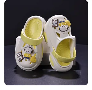 Vista dettagliata di zoccoli per bambini crema con accenti gialli e ciondoli di cartoni animati