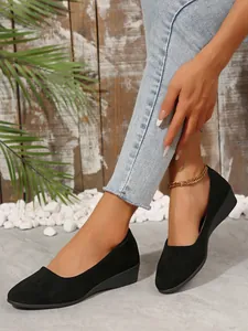 Nahaufnahme von schwarzen spitzen Keilpumps getragen mit Jeans und goldener Kette.