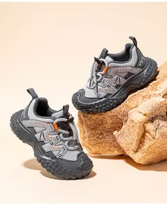 Breathable grey and orange children's closed-toe athletic sandals on outdoor rock prop