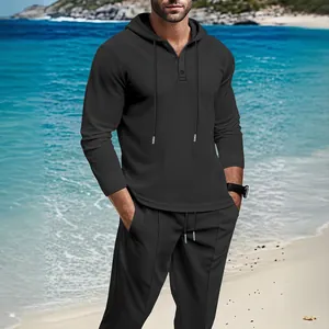 Detail view of men's dark gray waffle knit hoodie and pants set in a beach setting