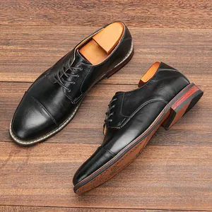 Close-up view of classic black men's formal leather derby shoes on a dark wooden floor