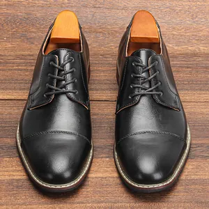 Top view detail of classic black men's leather business shoes on wooden floor texture