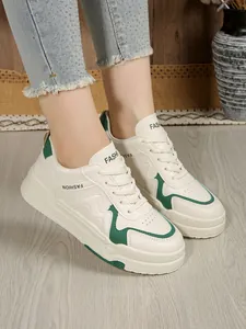 Πλαϊνή όψη κομψών λευκών δερμάτινων sneakers πλατφόρμας με πράσινες λεπτομέρειες σε μοντέλο