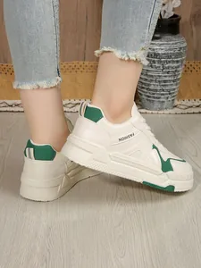 Κοντινό πλάνο με λευκά δερμάτινα γυναικεία sneakers με πράσινες λεπτομέρειες και παχύ πάτο.