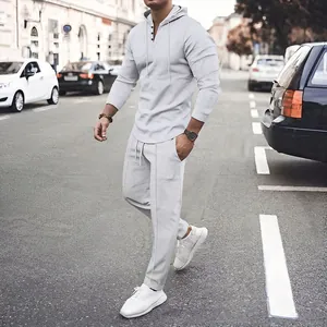 Men's light grey waffle knit hoodie and pants set shown in a stylish urban street setting