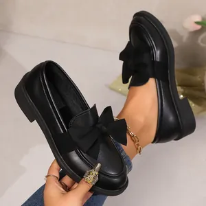 Vue détaillée de mocassins noirs à plateforme avec un nœud élégant et texture cuir
