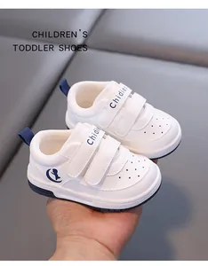 Detailed view of white toddler sneakers with blue accents and double velcro straps.