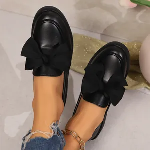 Gros plan de mocassins noirs à plateforme avec d'élégants nœuds en ruban sur mannequin.