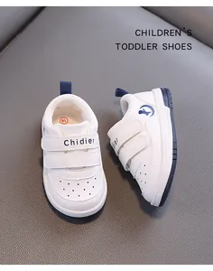 Close-up of white toddler walking shoes with double velcro straps and navy blue details.