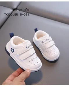 Detail view of white toddler walking shoes with navy blue velcro straps and soft soles.