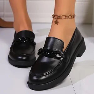 Gros plan de mocassins noirs à plateforme avec détail de chaîne sur une finition lisse