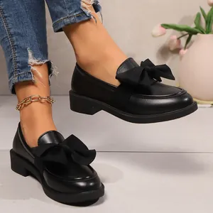 Gros plan de mocassins à plateforme noirs avec nœud géant et semelle épaisse