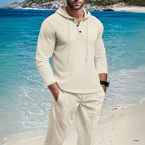 Men's cream waffle knit hoodie and pants set shown in a scenic beach resort setting.