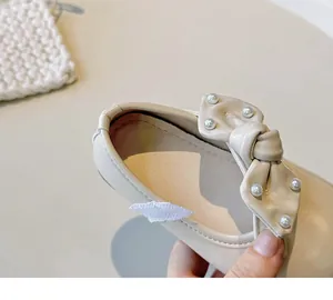 Detaillierte Makroansicht von cremefarbenen Prinzessinnenschuhen für Mädchen mit Perlenbogen.