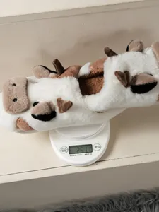 Detailopname van het gewicht van een pluche koe-pantoffel op een weegschaal, ca. 251g