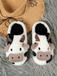 Dichtbij van schattige pluche koeienslippers op een grijs wollen kleed