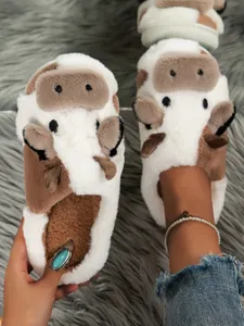 Detailopname van pluche pantoffels met koeienprint en zachte textuur voor in huis