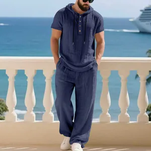 Men's navy blue linen-textured hooded Henley shirt and loose trousers set outdoors.