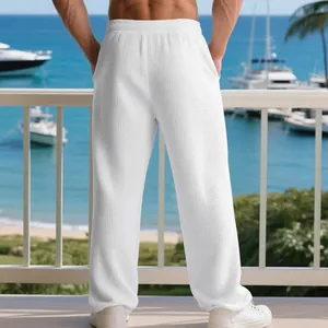 Detail of men's white waffle texture trousers against a scenic ocean background