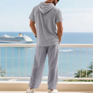 Men's loose linen set featuring a grey hooded short sleeve top and pants on a resort balcony