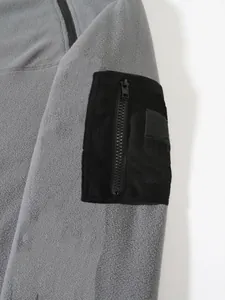 Gros plan de la poche zippée noire sur la manche d'une veste en polaire corail grise