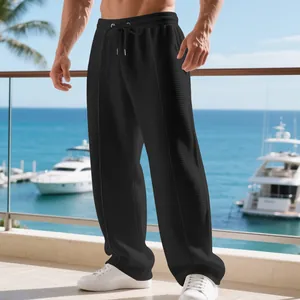 Detailed view of men's loose black waffle-knit straight-leg sports pants in a resort setting