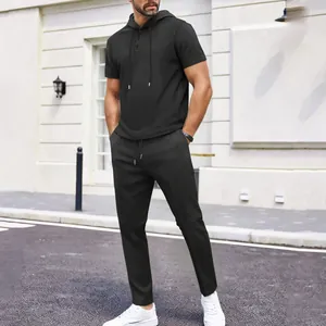 Lifestyle view of a man wearing a black waffle knit hooded top and matching pants