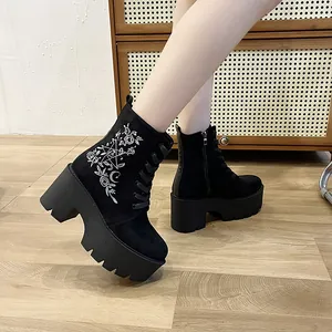 Nahaufnahme schwarzer Plateaustiefel mit eleganter Blumenstickerei und grober Profilsohle.