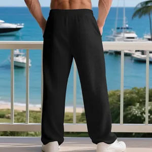 Back view of men's casual black waffle texture loose straight pants in a beach setting