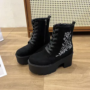 Detailansicht schwarzer Plateaustiefel mit weißer Blumenstickerei und Reißverschluss.