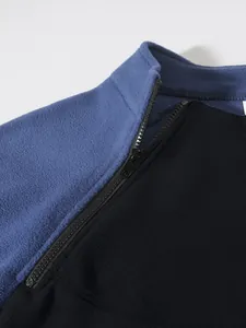Gros plan sur le col montant et la fermeture éclair d'une veste polaire douce bleue et noire