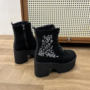 Seitenansicht schwarzer Plateau-Stiefeletten mit aufwendiger weißer Blumenstickerei-Details