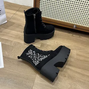 Nahaufnahme schwarzer Plateau-Stiefel mit weißer Blumen- und Sternstickerei