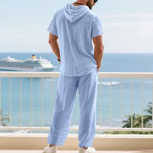 Back view of men's light blue linen hooded shirt and trousers set on a scenic balcony